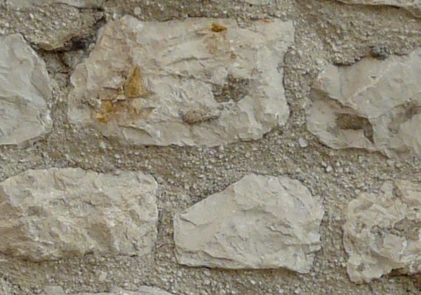 Beige stone set in arrays in wall surface.